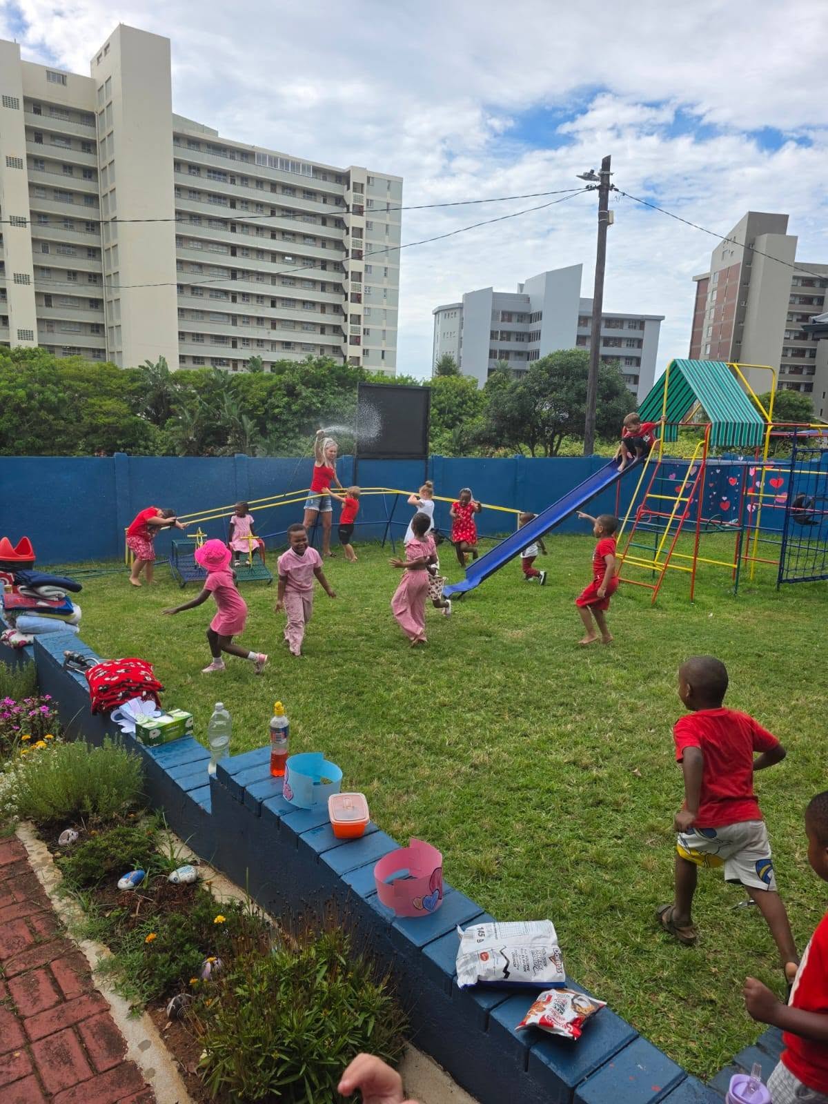 Children playing together on the grass and slide in the Emojis playground